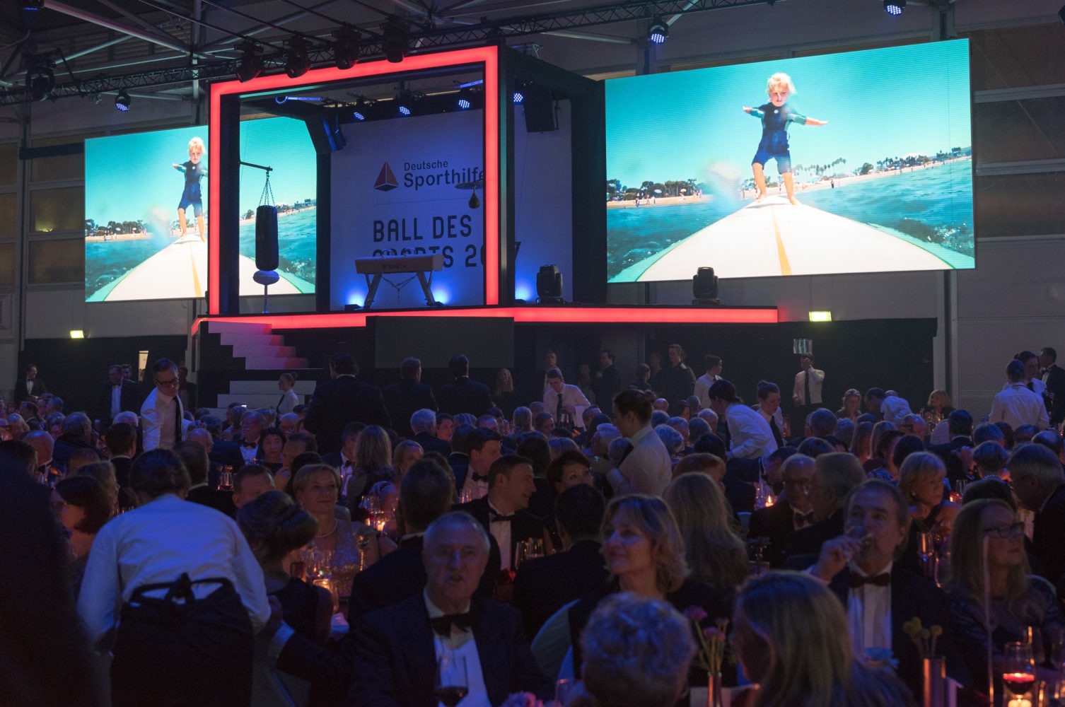 Festsaal gefüllt mit Gästen bei der "Ball des Sports"-Gala 2017 in Wiesbaden. Im Hintergrund eine Leinwand mit dem Logo der Deutschen Sporthilfe und einer Sportlerin beim Hochsprung.