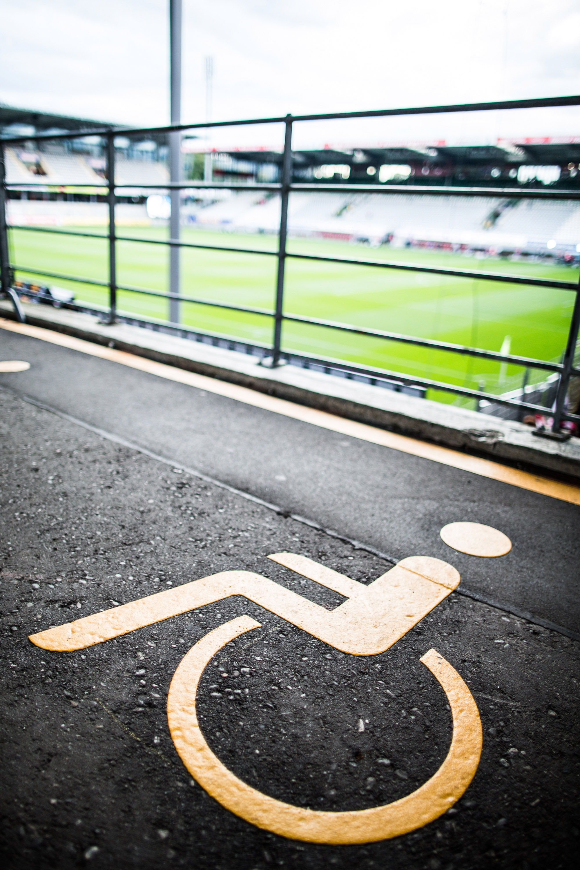 Symbol für Rollstuhlfahrer auf dem Boden vor einer Tribüne im Fußballstadion.