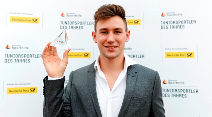 Niklas Kaul, Zehnkämpfer, hält die Auszeichnung "Juniorsportler des Jahres 2017" in die Höhe. Hinter ihm ist ein Banner mit dem Aufdruck "Juniorsportler des Jahres" zu sehen.