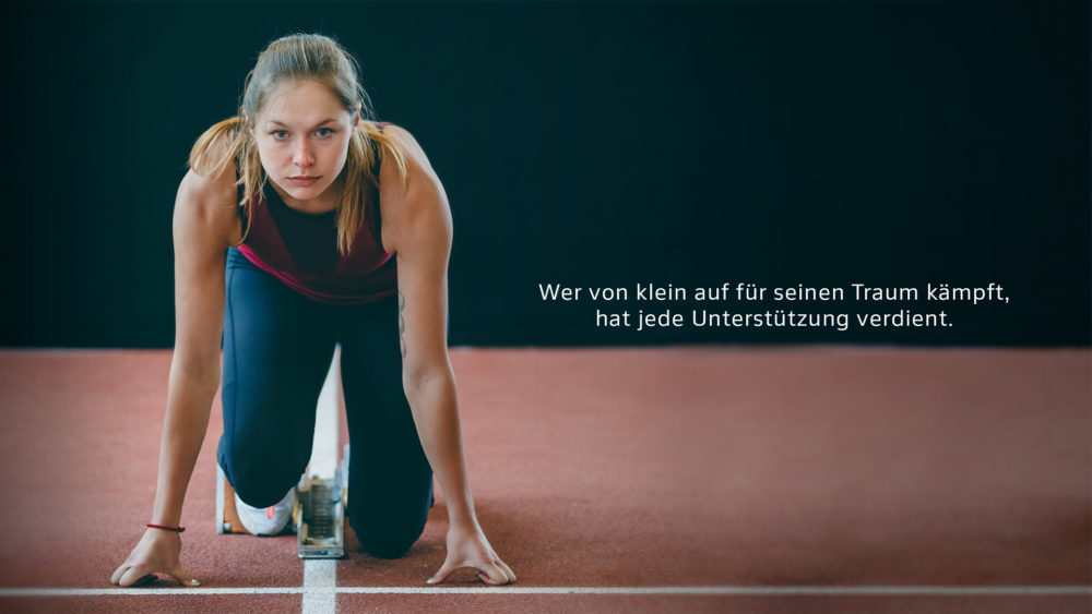 Eine Sportlerin in Startposition auf einer Laufbahn, entschlossen und fokussiert.