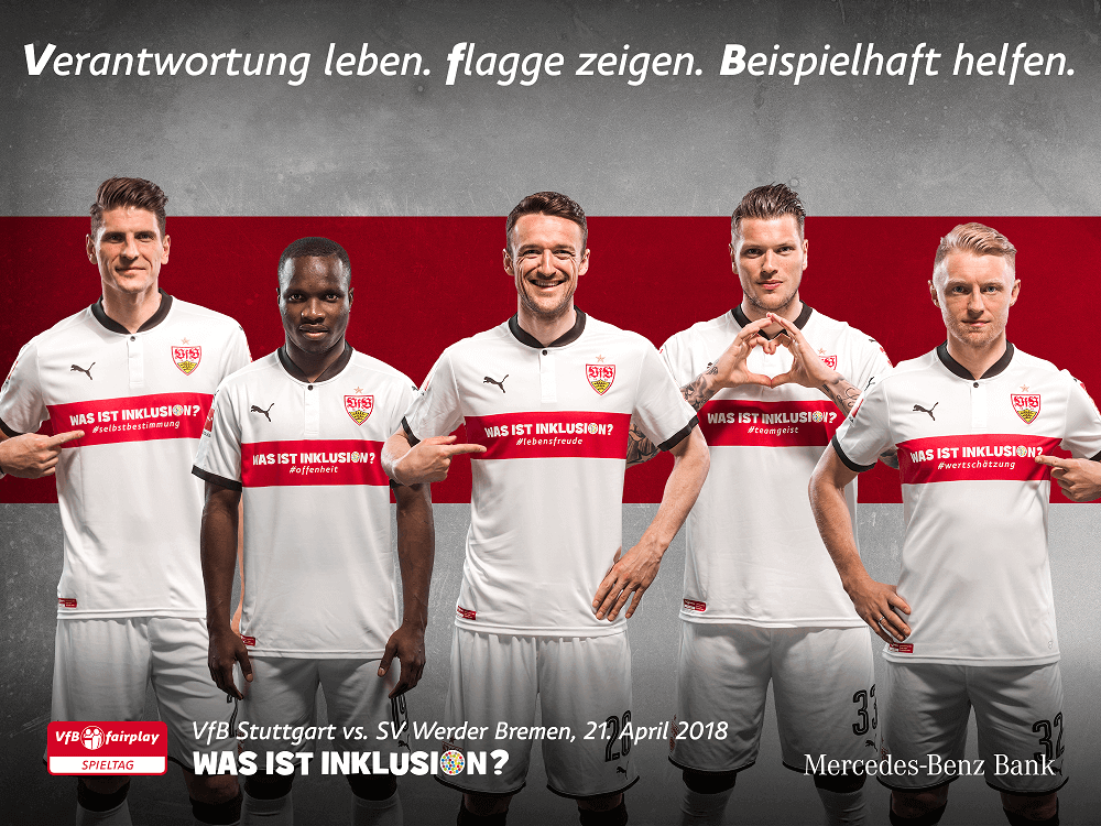 Fünf Fußballspieler des VfB Stuttgart stehen in Formation vor der Kamera und halten Schilder mit der Aufschrift "WAS IST INKLUSION?" in verschiedenen Sprachen. Sie tragen weiße Trikots mit dem VfB-Logo und werden von Mercedes-Benz Bank gesponsert. Im Hintergrund steht "VfBfairplay Spieltag".