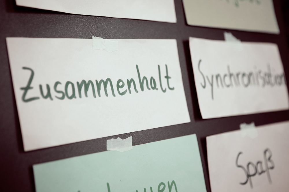 Klebezettel mit handschriftlichen Begriffen "Zusammenhalt" und "Spaß" an einer Wand, im Kontext eines Workshops für Kinder im Rahmen des Projekts "Lernort Stadion" der DFL Stiftung.