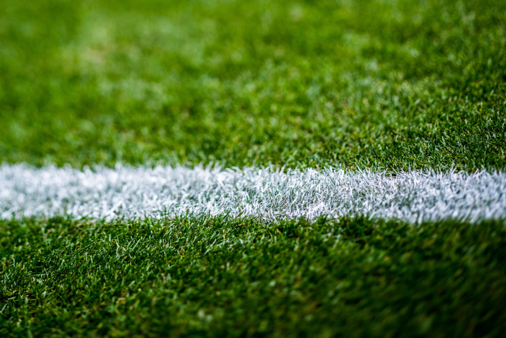 Grüne Fußballrasenfläche mit weißer Linierung.