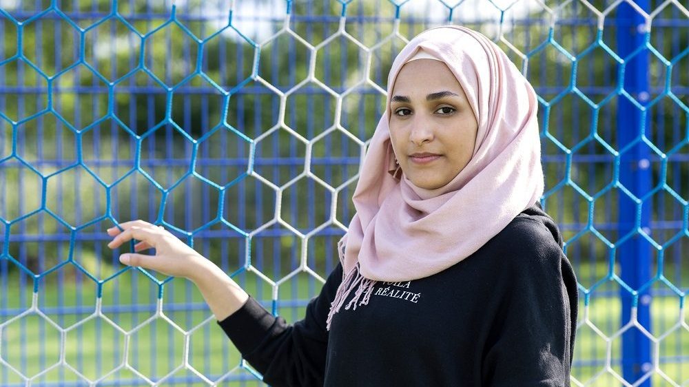 Das Mädel steht vor dem Tor und hält das Netz in der Hand