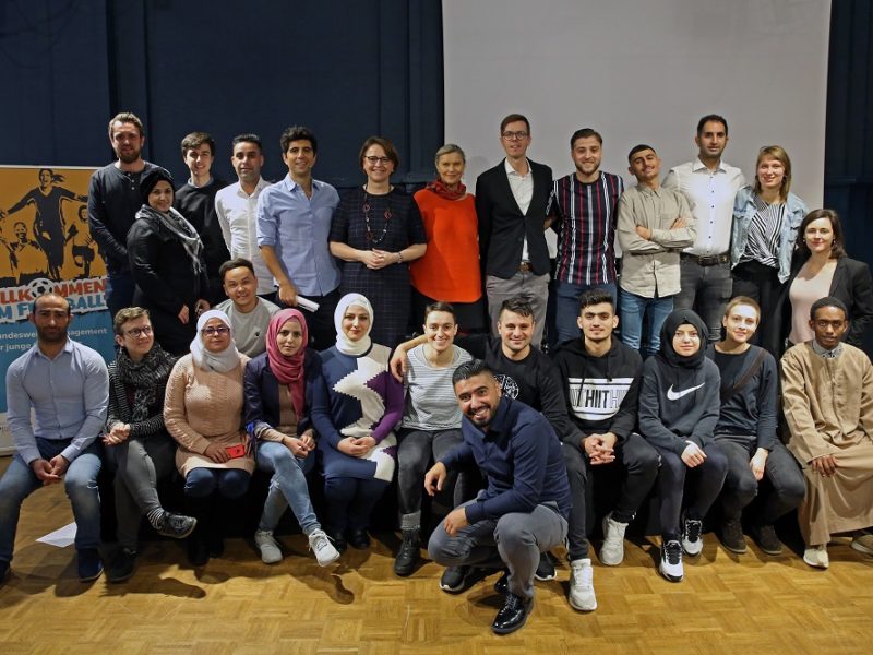 Gruppe von Teilnehmenden und Mitarbeitenden der DFL Stiftung bei einer Ergebnispräsentation des Projekts "Willkommen im Fußball" in Berlin.