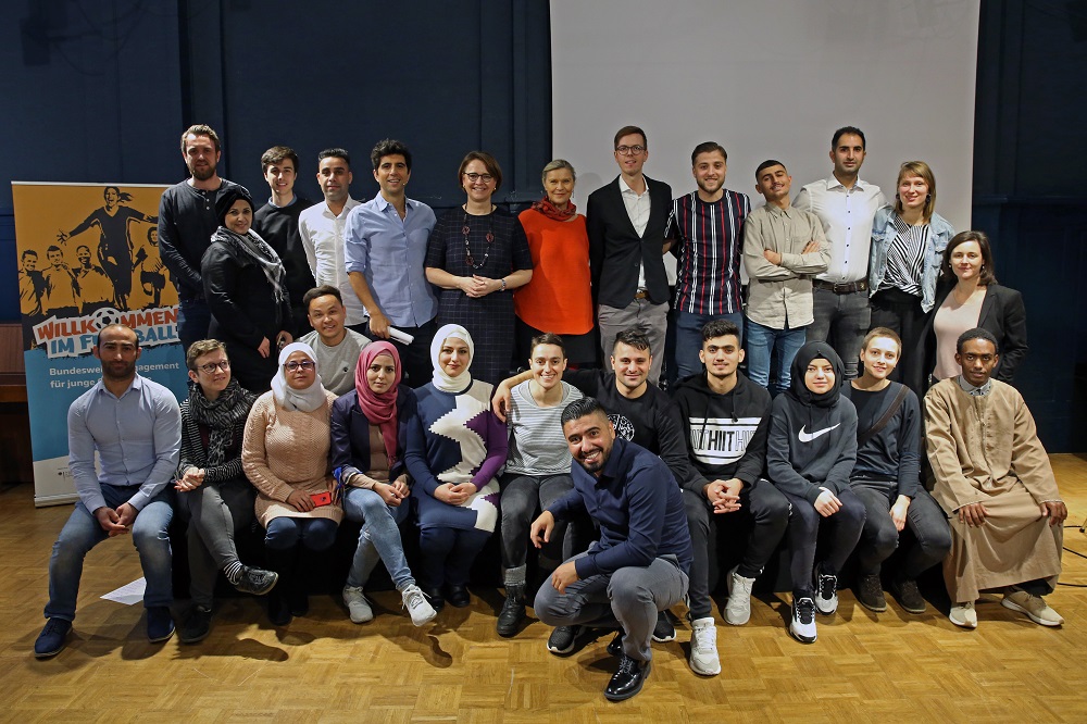 Gruppe von Teilnehmenden und Mitarbeitenden der DFL Stiftung bei einer Ergebnispräsentation des Projekts "Willkommen im Fußball" in Berlin.