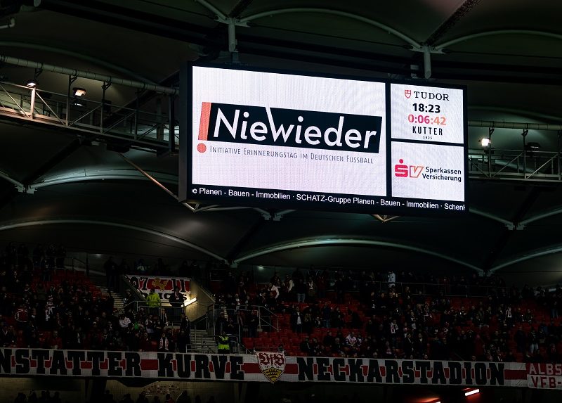 Anzeigetafel im Fußballstadion mit der Aufschrift "Nie wieder" und dem Hinweis auf den Erinnerungstag im Deutschen Fußball.