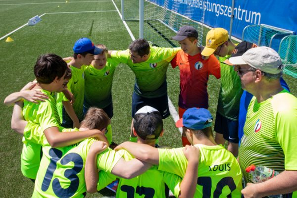 Eine Fußballmannschaft steht auf dem Rasen im Kreis zusammen. Die Spieler haben die Arme über die Schultern der Mitspieler gelegt.