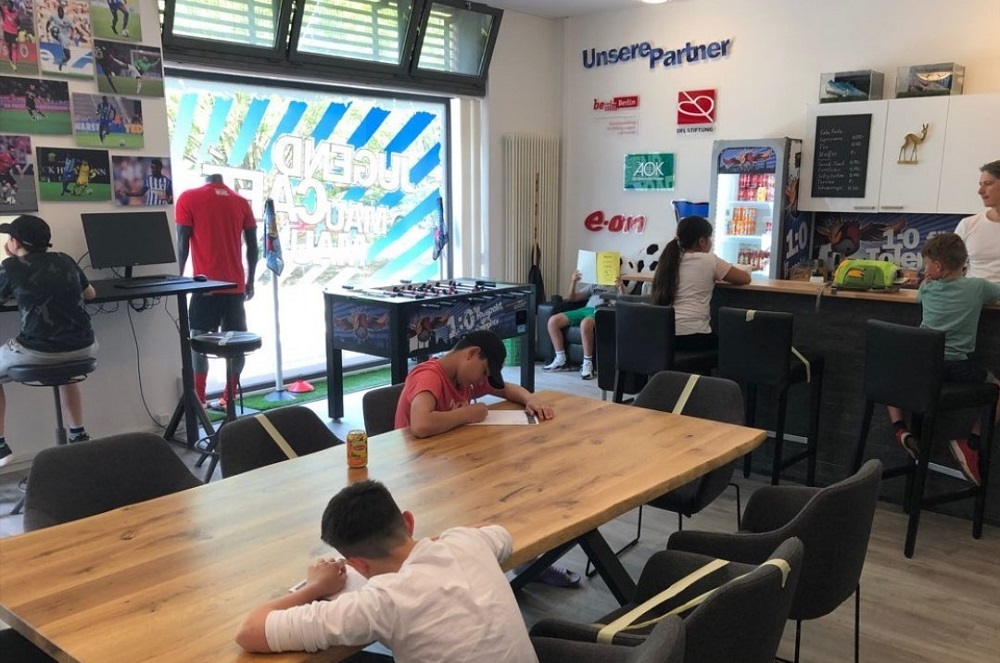 Kinder sitzen im Jugend Café und schreiben und lesen