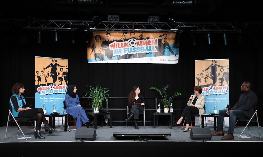 Vier Frauen und ein Mann sitzen auf Stühlen im Halbkreis auf dem Podium