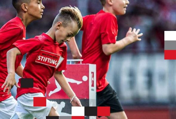 Drei junge Fußballspieler mit rotem Trikot, auf denen 