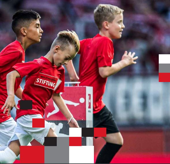 Drei junge Fußballspieler mit rotem Trikot, auf denen 