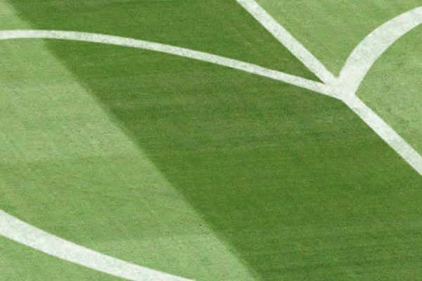 Grüner Rasen eines Fußballstadions mit einer weißen Herzform als Markierung, Symbolbild für die Arbeit der DFL Stiftung.