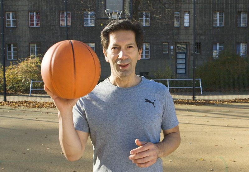 Sport- und Gymnastiklehrer steht hält den Basketball in seiner rechten Hand