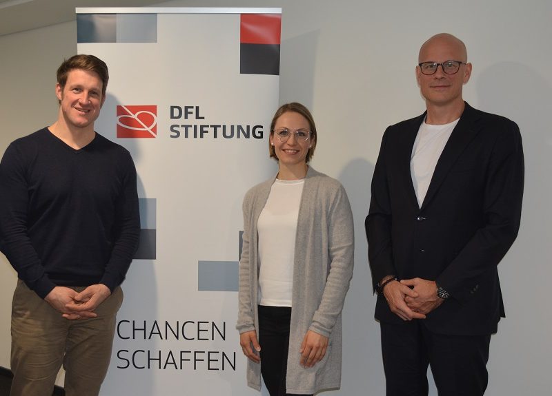 Bild von Matthias Steiner, Magdalena Neuner und prof. Dr. Dr. Stefan Schneiderneben dem Plakat der DFL Stiftung