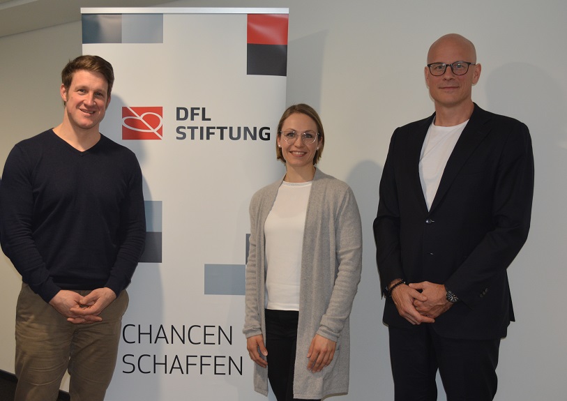 Bild von Matthias Steiner, Magdalena Neuner und prof. Dr. Dr. Stefan Schneiderneben dem Plakat der DFL Stiftung