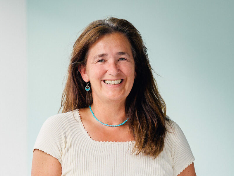 Clarissa Sagerer-Schlockermann, lächelnde Frau mit langen braunen Haaren vor hellem Hintergrund.