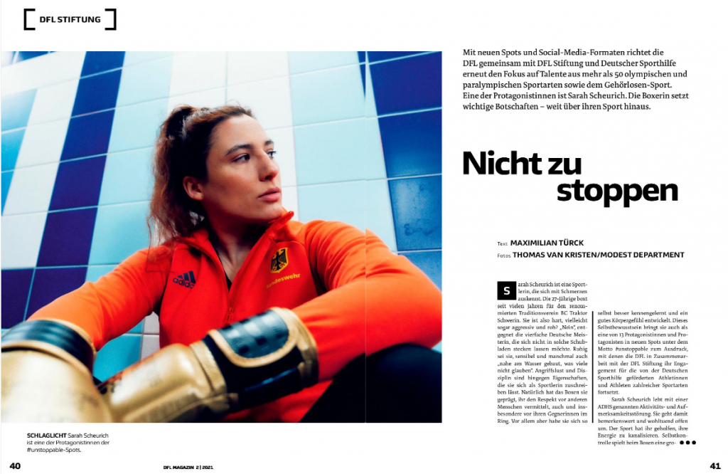 Sarah Scheurich, eine Boxerin, trägt Trainingskleidung und schaut entschlossen in die Kamera. Im Hintergrund ist ein Trainingsraum zu sehen.