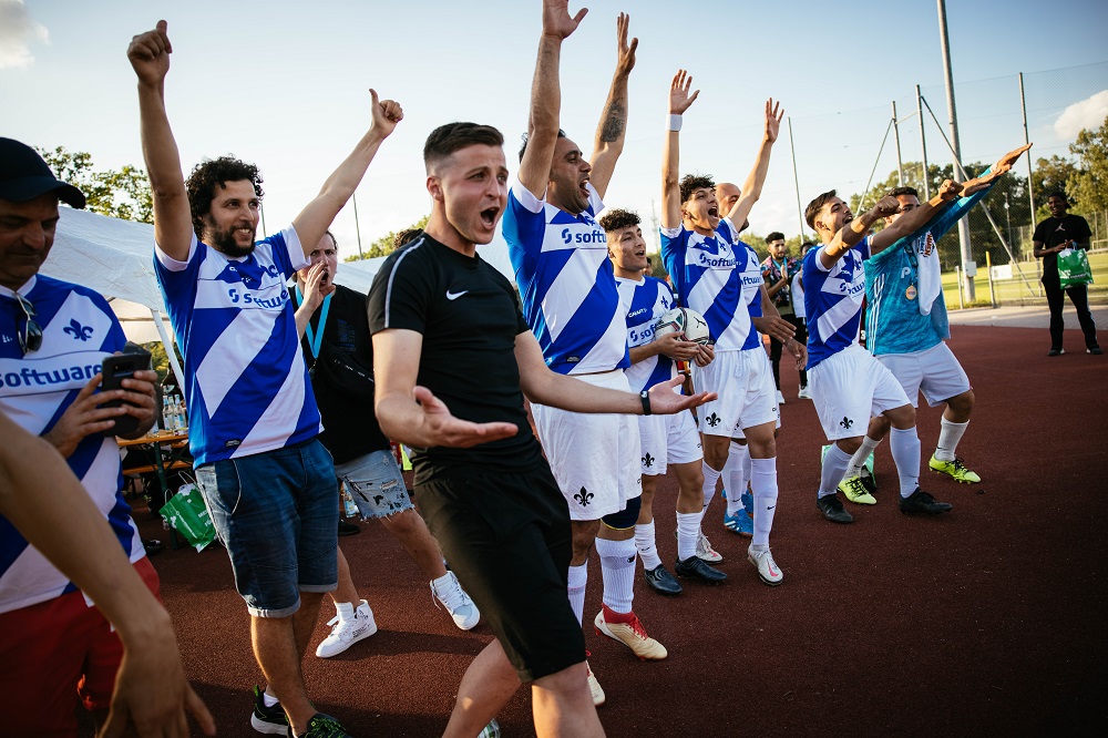 Jubelnde Fußballmannschaft in blau-weißen Trikots nach einem Spiel beim regionalen "Willkommen im Fußball"-Cup in Fürth.