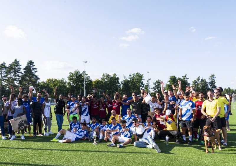 Alle Teilnehmenden des 5. lokalen „Willkommen im Fußball“-Cups stehen auf dem Fußballfeld