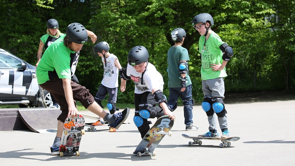Die Teilnehmenden fahren Skateboards auf dem Spielplatz.