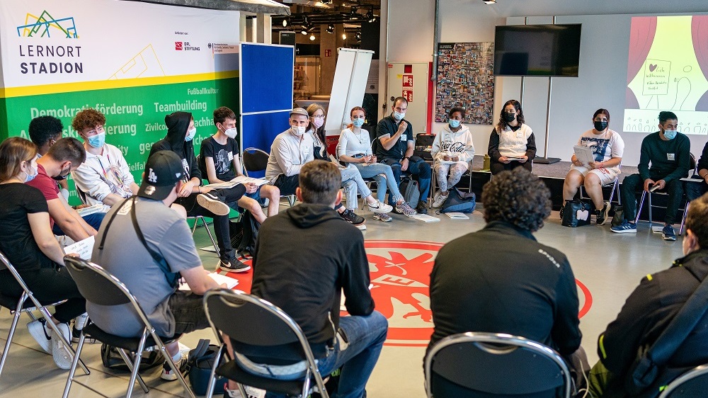 Die Teilnehmenden sitzen auf den Stühlen in einem Kreis.