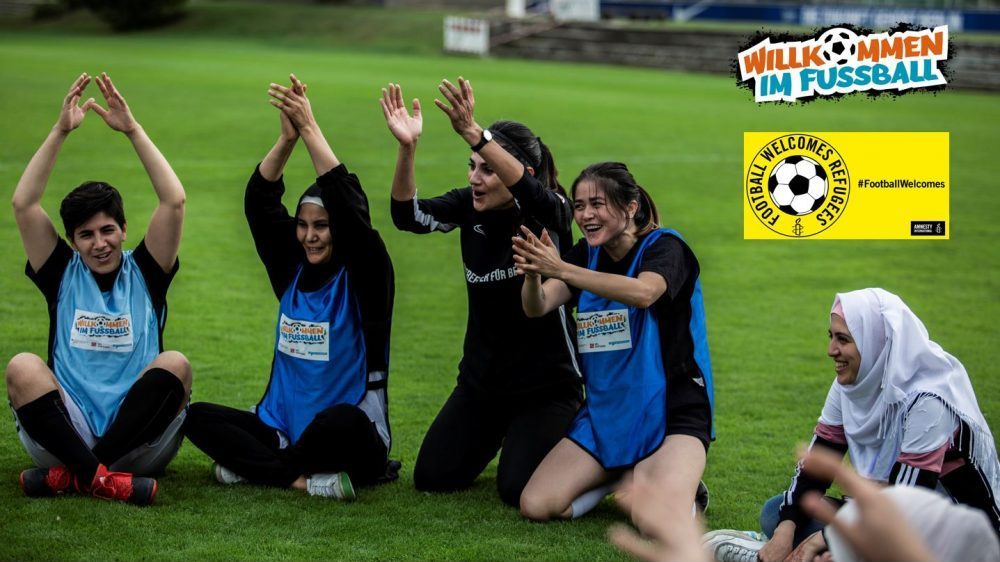 Mädchen sitzen auf dem Fußballfeld und jubeln.