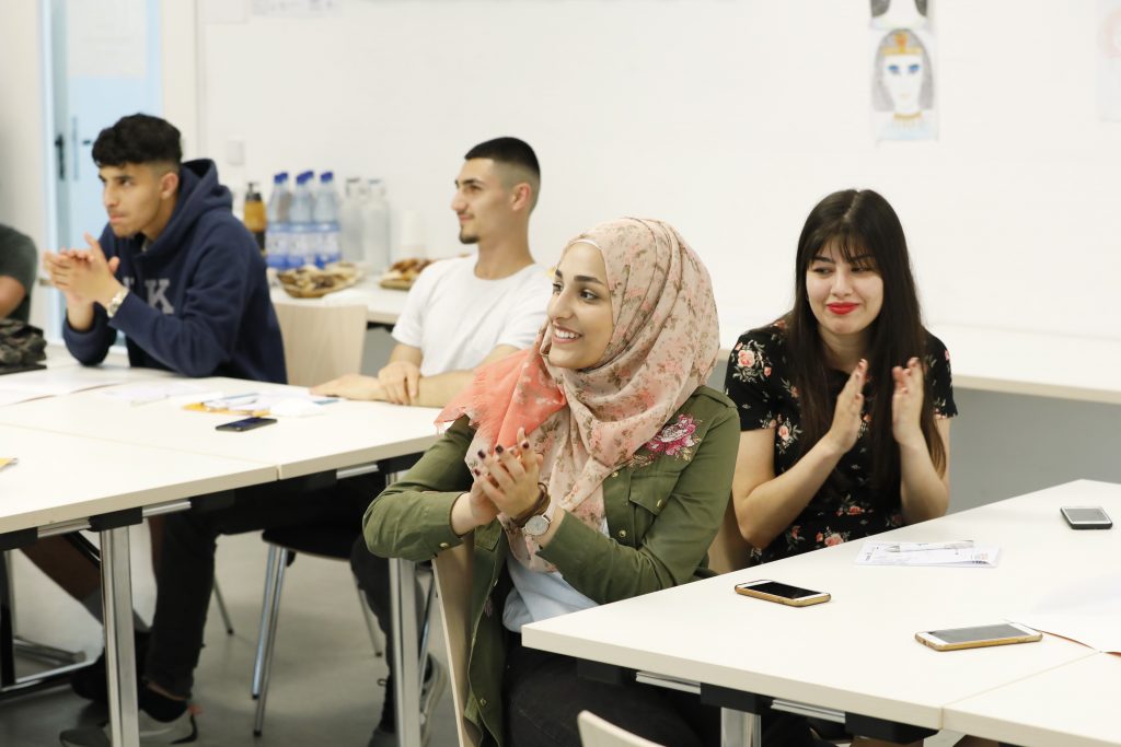 Jugendliche sitzen im Workshop und klatschen.