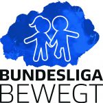 Eine Gruppe von Kindern in weißen T-Shirts mit dem Aufdruck "LITAN" steht auf einer Bühne und hält einen Pokal. Im Hintergrund stehen Erwachsene, darunter Männer in Anzügen, die einen übergroßen Scheck mit der Aufschrift "5000 Euro" halten. Im Hintergrund sind weitere Zuschauer zu sehen.