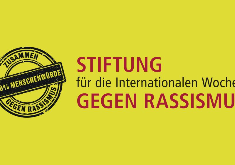 Schwarzer Stempel "Zusammen gegen Rassismus; 100 Prozent Menschenwürde" und "Stiftung für die Internationalen Wochen gegen Rassismus" auf gelbem Hintergrund.