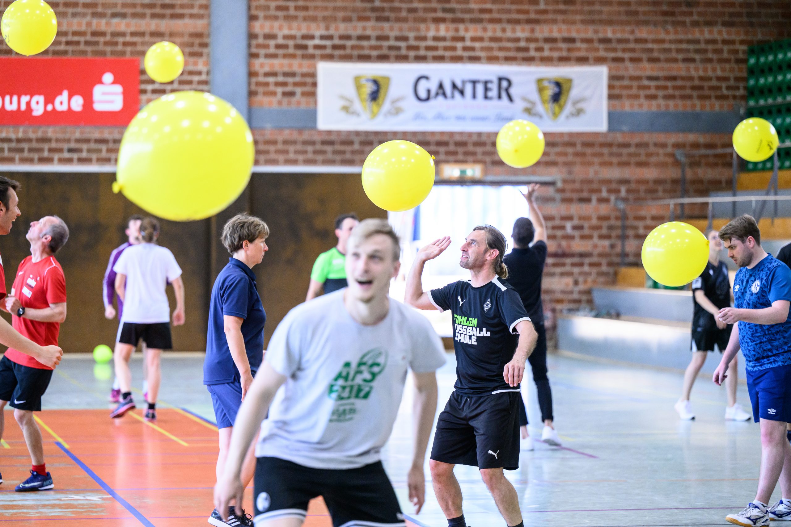 Drei begeisterte Fußballspieler im grünen Trikot stehen auf einem Podest und freuen sich, vermutlich über einen Gewinn beim FußballFreunde-Cup Nordost 2018. Im Hintergrund sind Werbebanner und das Spielfeld zu sehen.