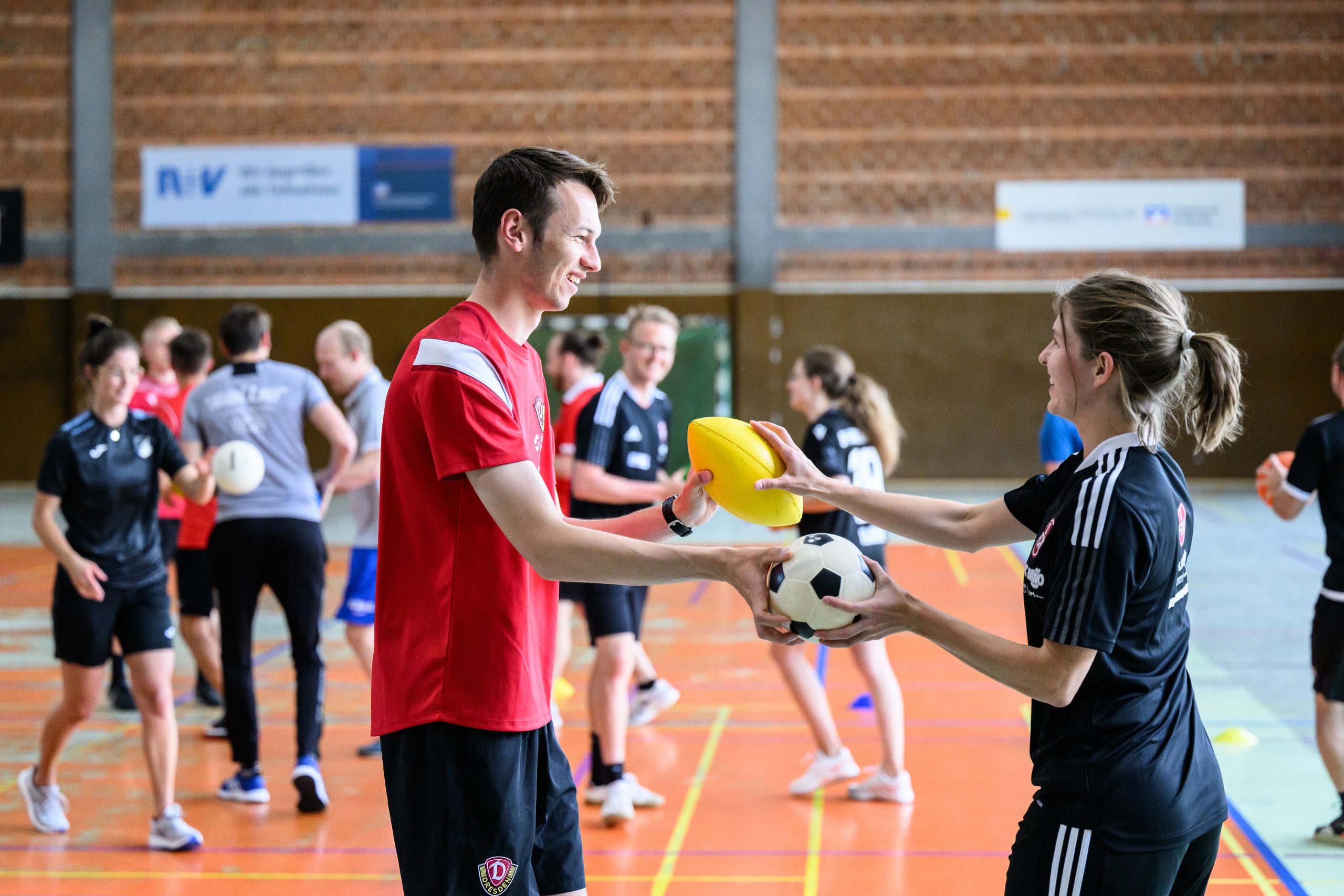 Maskottchen Bulli von RB Leipzig umarmt zwei junge Fußballspieler beim FußballFreunde-Cup Nordost 2018.