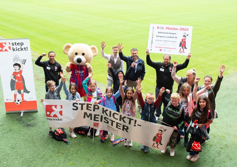 Die Sieger der step kickt!-Challenge aus Heidenheim stehen mit Bannern auf dem Stadionrasen und freuen sich.