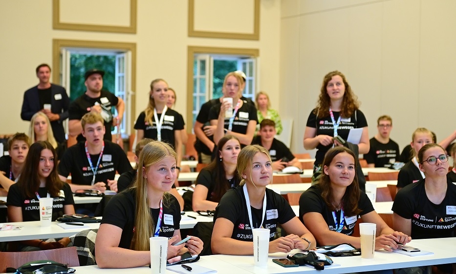 Die NEF-Athlet*innen sitzen an Tischen im Hörsaal.