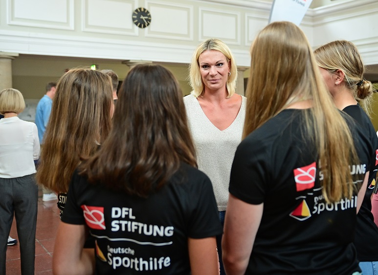 Maria Höfl-Riesch steht in einer Gruppe mit mehreren NEF-Athletinnen.