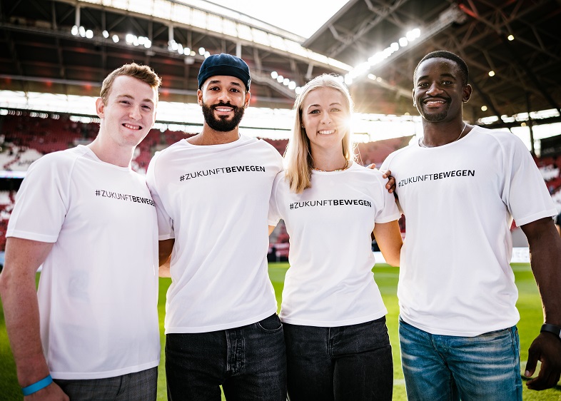 Drei der Athleten und eine Athletin stehen auf dem Stadionrasen.