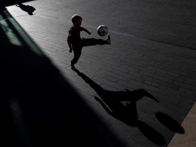 Ein kleines Kind spielt im Dunkeln mit einem Ball.
