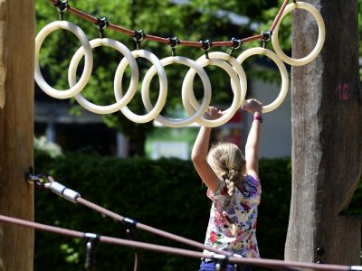 A girl shimmies along rings on a playground.