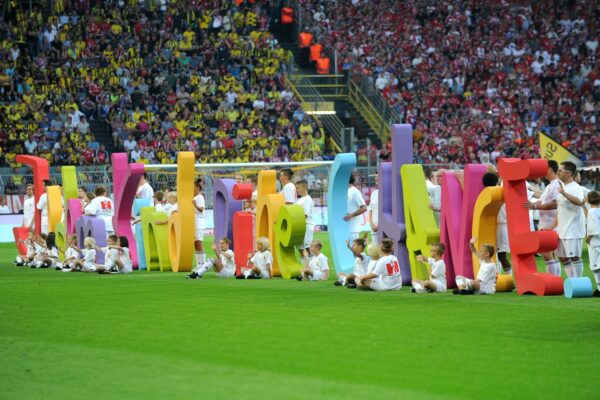 Many children in a stadium holding "Every child a chance" in big letters