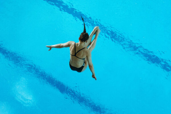 Lena Hentschel ist Wasserspringerin und springt gerade im gestreckten Salto ins Wasser.