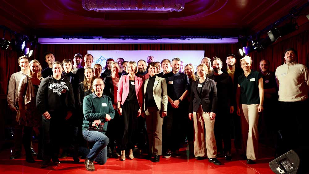 Eine Gruppe von Menschen steht dicht gedrängt in mehreren Reihen auf einer Bühne.