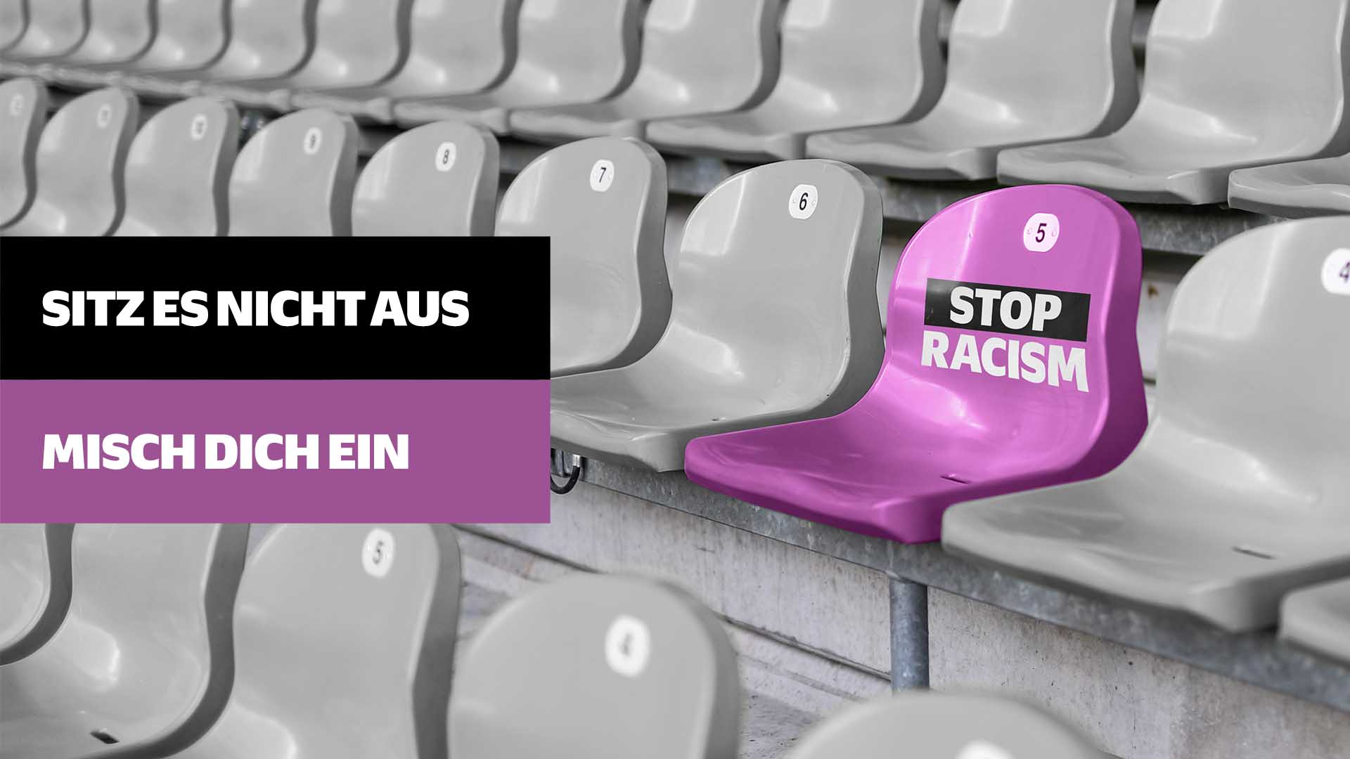 Ein leerer violetter Stadionstuhl mit dem Aufdruck "STOP RACISM" steht zwischen grauen Stadionstühlen. Im Vordergrund ein violettes Banner mit der Aufschrift "SITZ ES NICHT AUS - MISCH DICH EIN". Das Bild dient als Aufruf gegen Rassismus im Fußball.