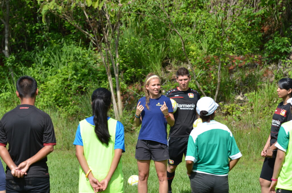 Lea Hinnen erklärt den Teilnehmenden die Übung auf dem Fußballfeld.