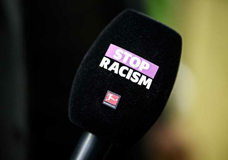 Mikrofon mit dem Aufdruck "STOP RACISM" und dem Logo der Bundesliga, Symbol für das Engagement gegen Rassismus im Fußball.