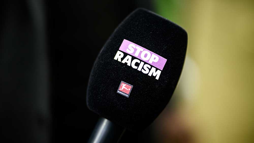 Mikrofon mit dem Aufdruck "STOP RACISM" und dem Logo der Bundesliga, Symbol für das Engagement gegen Rassismus im Fußball.
