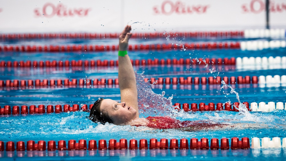 Schwimmerin Christina Altdorf bei den Special Olympics World Games 2023 im Schwimmbecken, im Begriff, mit dem Arm aus dem Wasser zu kommen.