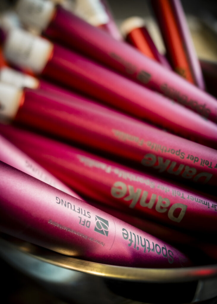 Staffelstäbe in Rosa mit Aufdruck "Danke" und Logo der Deutschen Sporthilfe, symbolisch überreicht an verabschiedete Athletinnen und Athleten für den Übergang in ihre zweite Karriere.