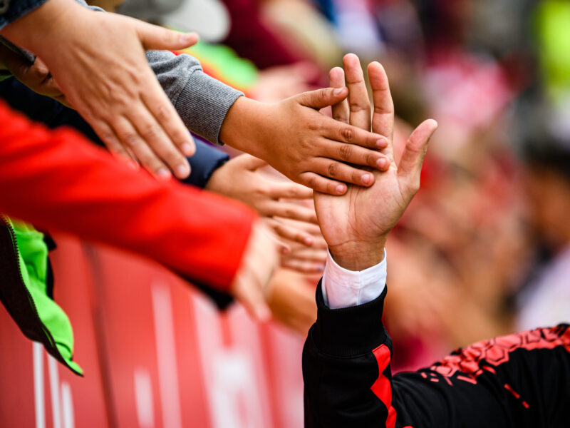 Spieler von Jahn Regensburg und Fans berühren sich mit den Händen nach einem Fußballspiel in der Continental Arena.