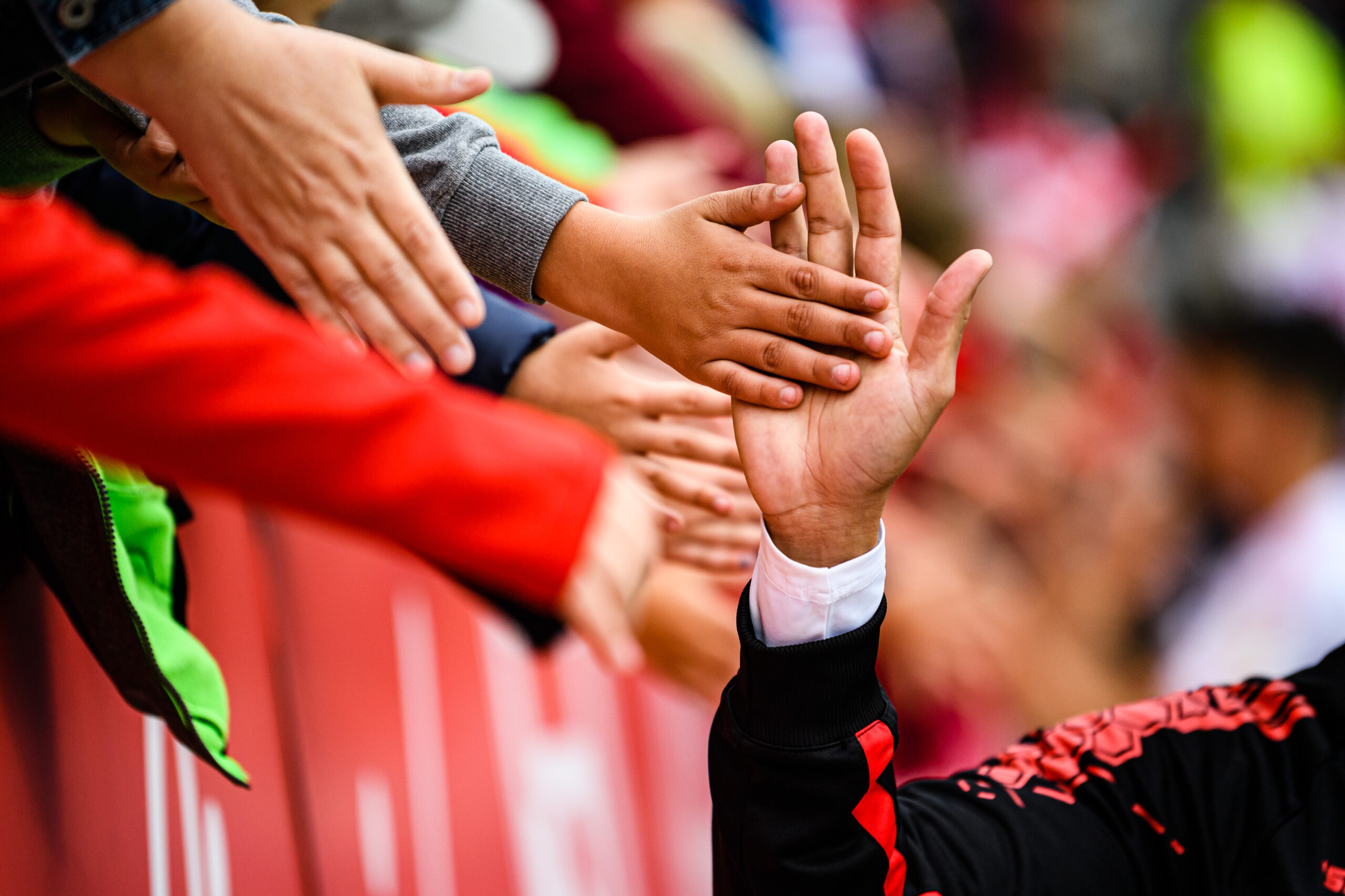 Spieler von Jahn Regensburg und Fans berühren sich mit den Händen nach einem Fußballspiel in der Continental Arena.