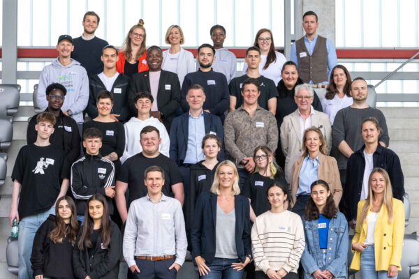 Ein Gruppenfoto des Kuratoriums der DFL Stiftung, aufgenommen auf den Sitzen eines Stadions. Die Mitglieder des Kuratoriums sind in mehreren Reihen angeordnet und schauen in die Kamera.